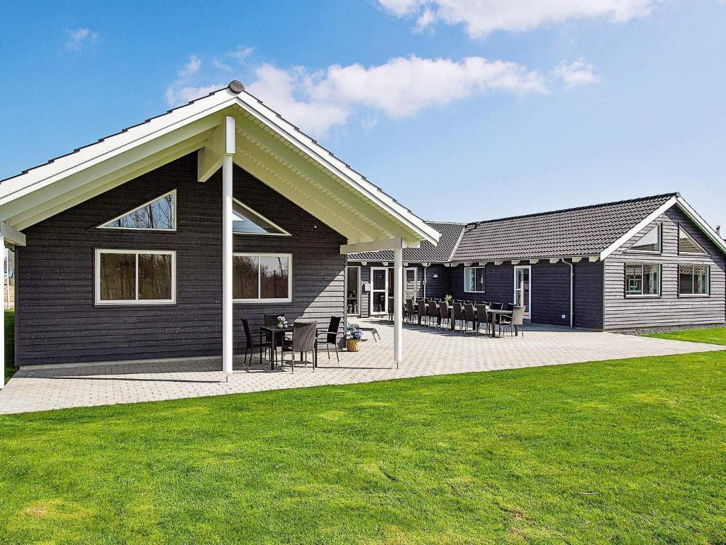 a black house with tables and chairs in a yard at 24 person holiday home in Hasselberg in Kappeln