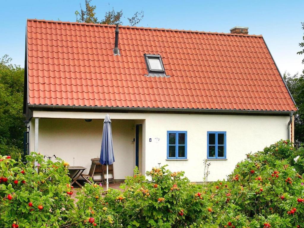 a white house with an orange roof and an umbrella at Ferienhaus im Hafendorf Vieregge in Vieregge