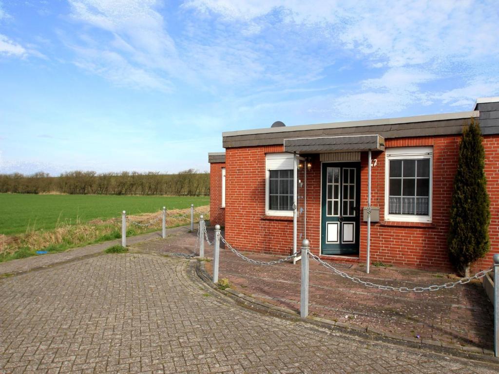 a red brick building with a fence around it at Holiday Bungalow in Dornumersiel in Dornumersiel