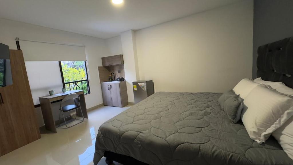 1 dormitorio con cama, escritorio y nevera en Venezia 208, en Cali