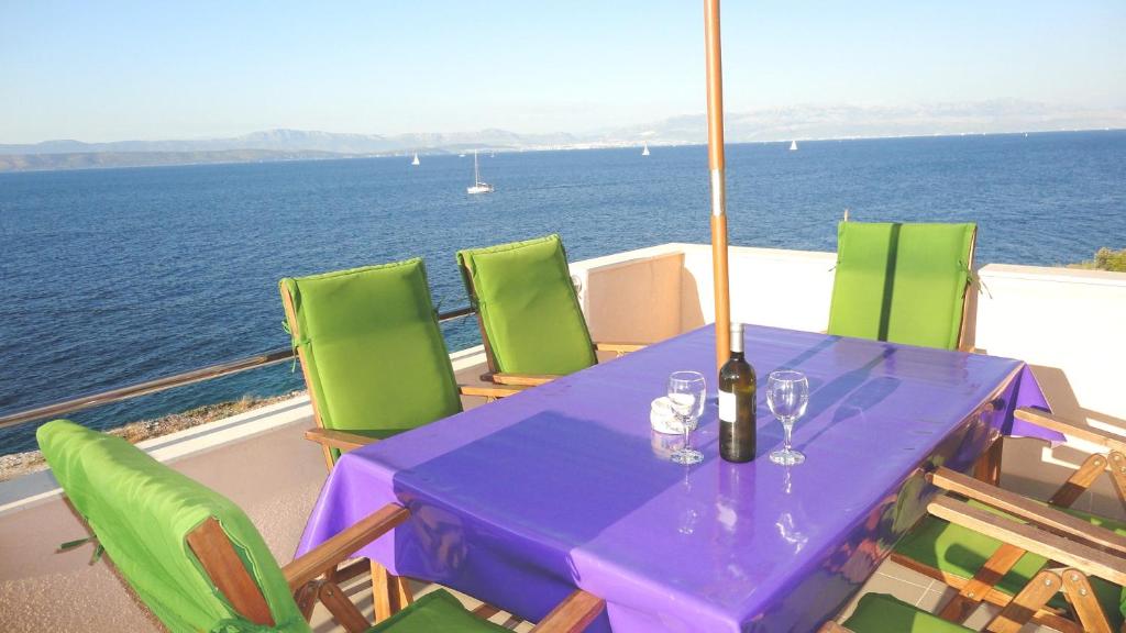 a purple table with chairs and a bottle of wine at Adriatic Escape in Rogač