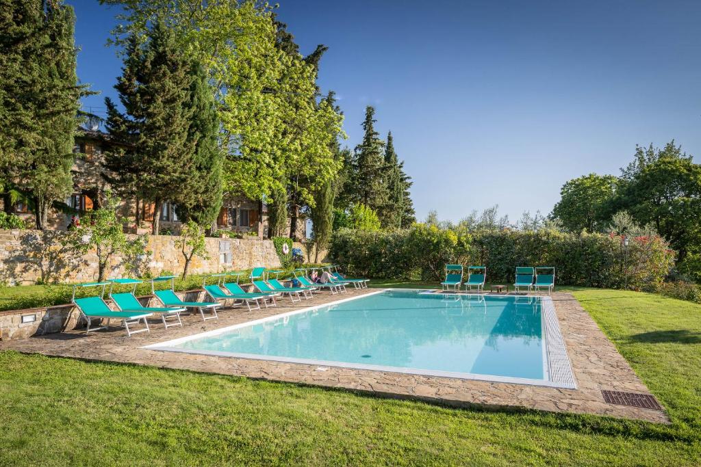 a swimming pool with lounge chairs in a yard at Le Cetinelle in Greve in Chianti