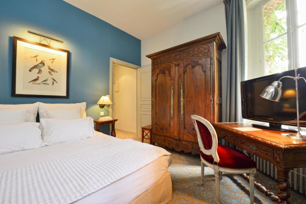 a bedroom with a bed and a desk with a television at Hôtel Le Saint Christophe in La Baule