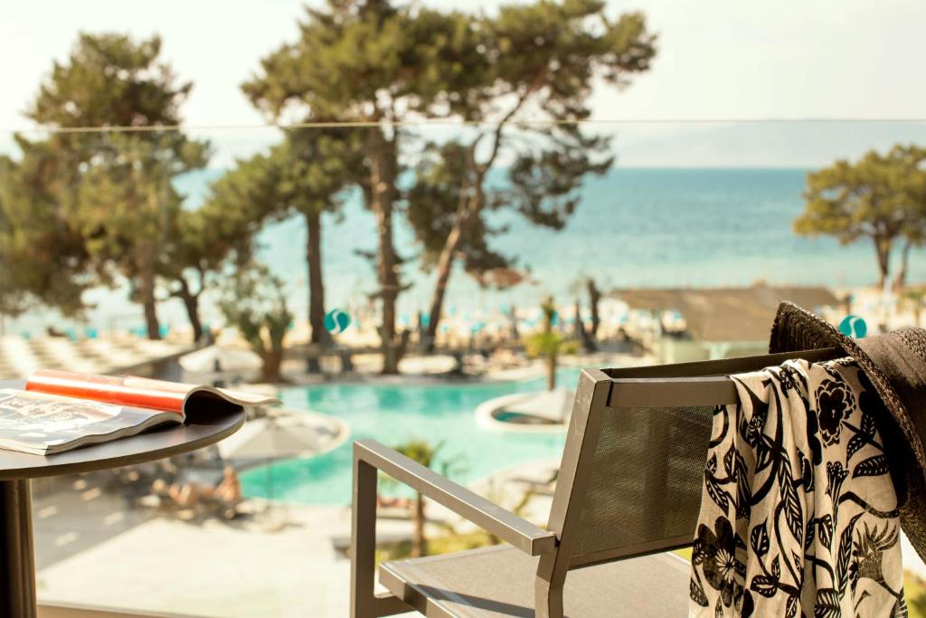 a chair with a table and a view of a pool at Sentido Thassos Imperial in Skala Rachoniou