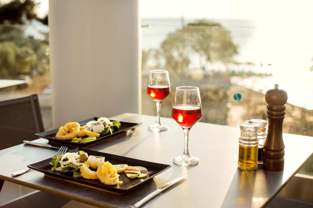 two plates of food and two glasses of wine on a table at Thassos Imperial Resort in Skala Rachoniou