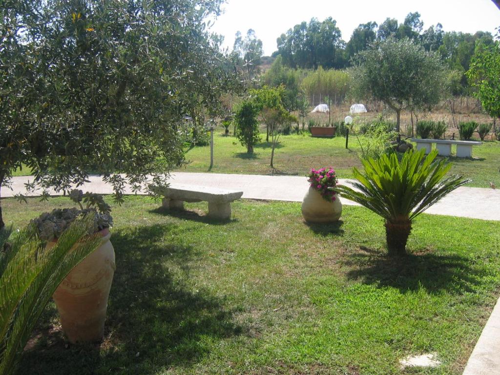 a park with a bench and plants in the grass at Le Mimose in Cala Liberotto