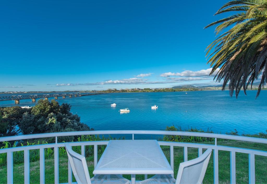 una mesa y sillas en un balcón con vistas al agua en The Tauranga on the Waterfront en Tauranga