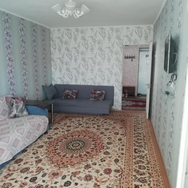 a living room with a blue couch and a rug at 20 дом у моря in Aktau