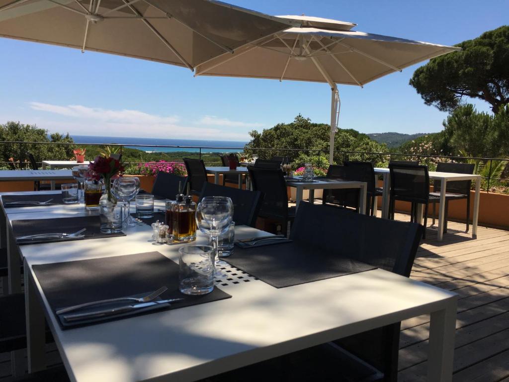 a restaurant with tables and chairs and an umbrella at Hôtel les Bouis - Vue mer in Saint-Tropez