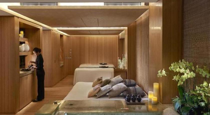 a woman standing in a room with a bed at The Landmark Mandarin Oriental, Hong Kong in Hong Kong