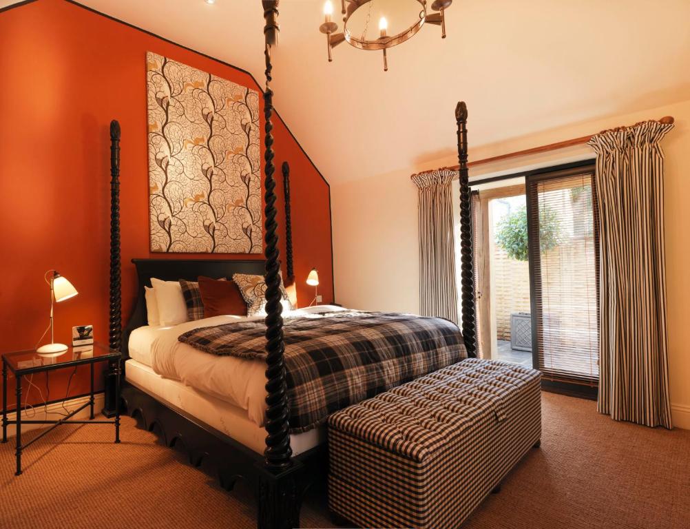 a bedroom with a canopy bed and a window at The Hare & Hounds Hotel in Tetbury