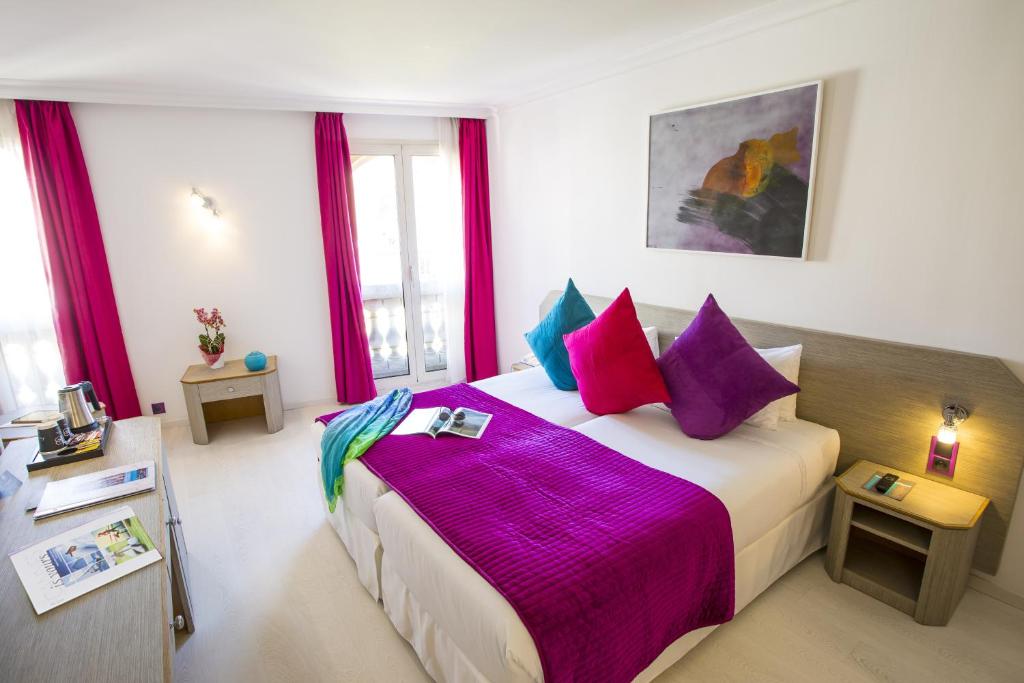 a bedroom with a large bed with purple sheets and pillows at Cristal Hôtel & Spa in Cannes