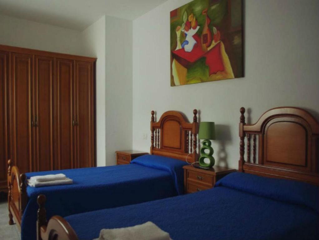 a bedroom with two beds with blue sheets at Pension Casa Curro in Palas de Rei