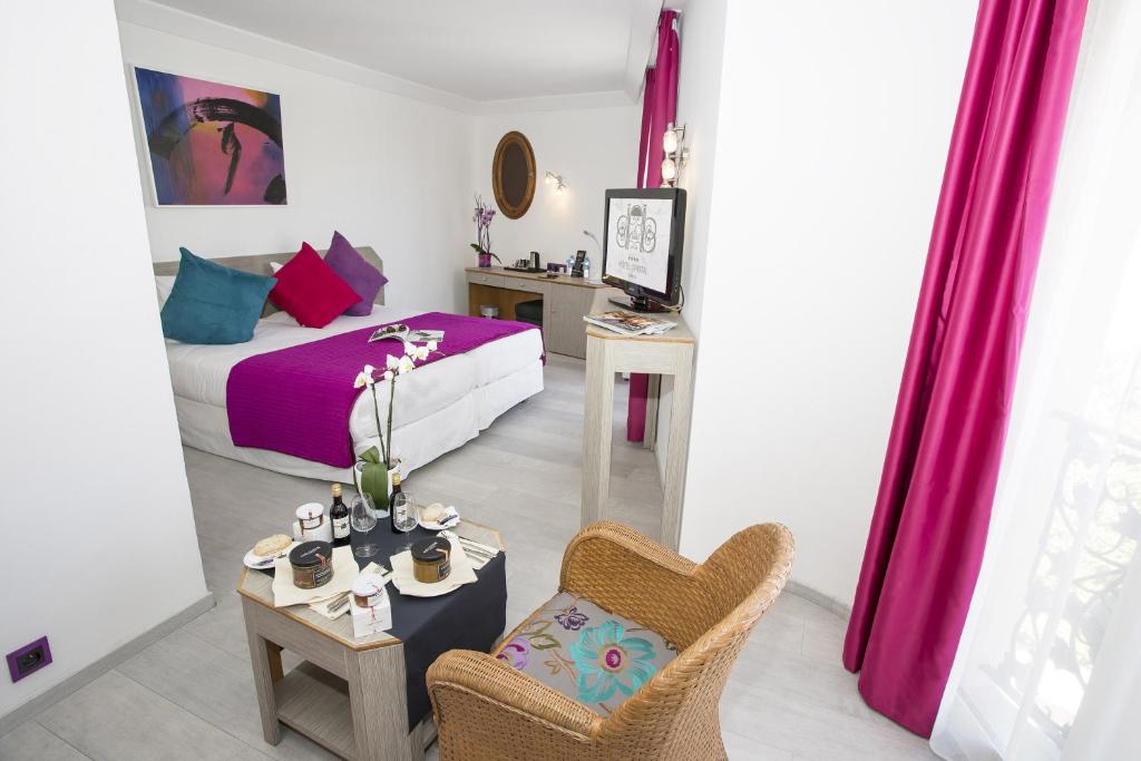 a bedroom with a bed and a table and a chair at Cristal Hôtel & Spa in Cannes