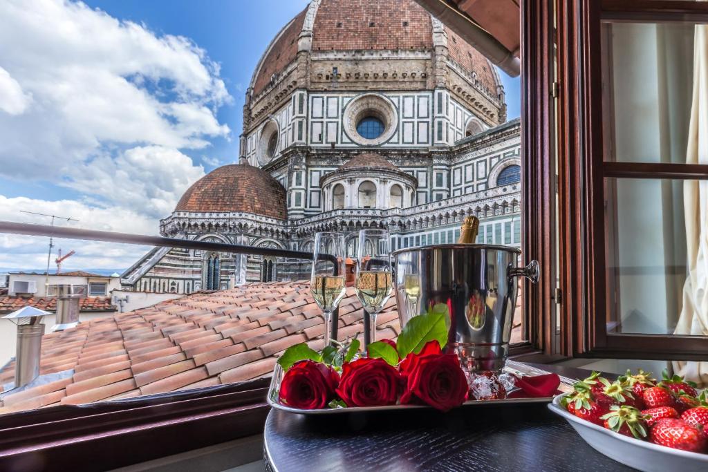 a table with roses in front of a window at Hotel Duomo Firenze in Florence
