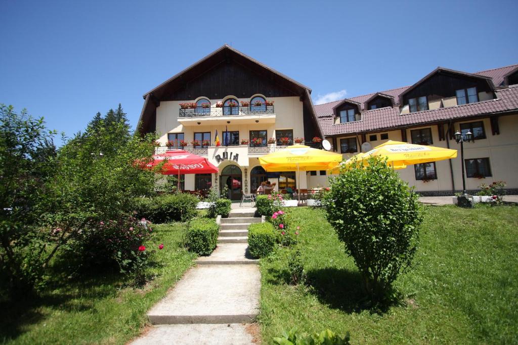 a building with umbrellas and a path in front of it at Hotel Ruia in Poiana Brasov