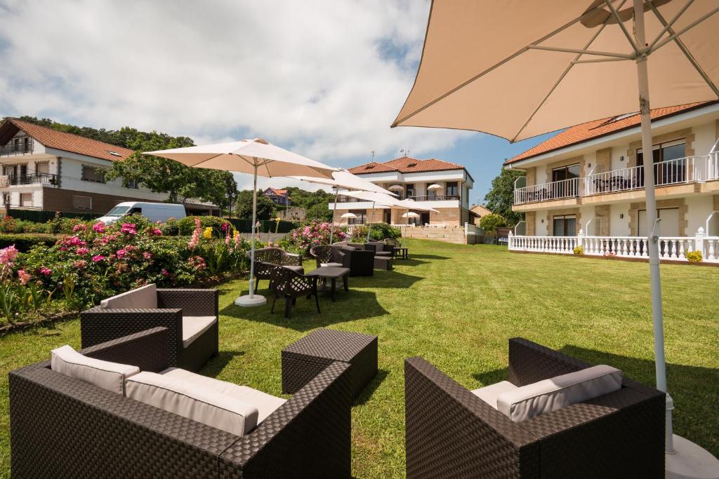 a patio with chairs and tables and an umbrella at Apartamentos La Bolera in Isla