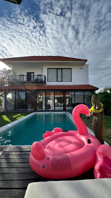 a pink inflatable swan in front of a swimming pool at Vila Billy II in Munggu