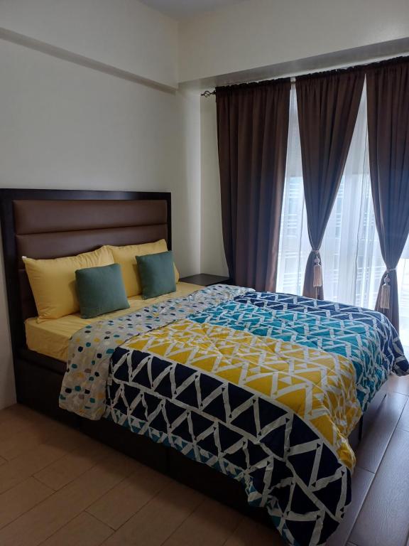 a bedroom with a large bed with blue and yellow sheets at Pasay 1BR Family Staycation with Parking in 150 Newport Boulevard near Resort World & NAIA T3 in Manila
