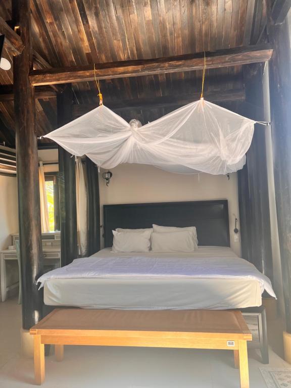 un lit avec une moustiquaire au-dessus avec un banc dans l'établissement Bently Farm Retreat Mũi Né-Premium bungalow-06, à Ấp Phú Hiệp