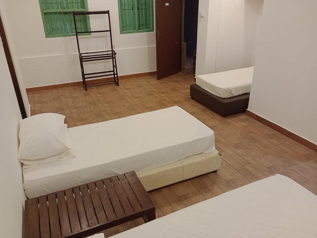 a room with two beds and a chair in it at Waves Hostel in Negombo