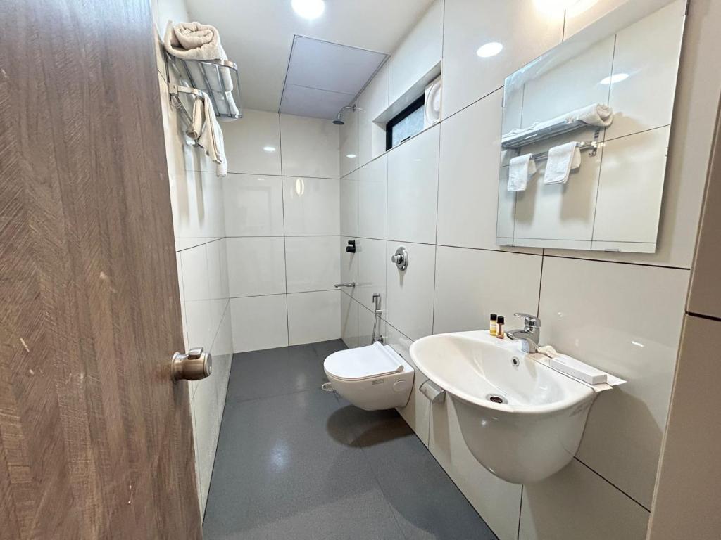 a white bathroom with a toilet and a sink at SwagStay Hotel Riviera Grand, Nagpur in Nagpur