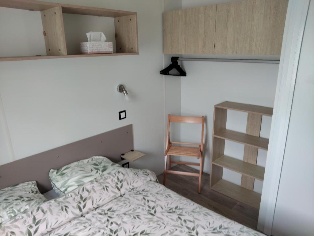 ein Schlafzimmer mit einem Bett und einem Holzstuhl in der Unterkunft Mobil home le Sunny in Lège-Cap-Ferret