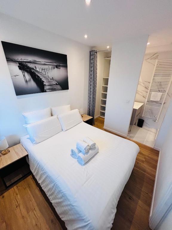 a bedroom with a large white bed with two towels on it at L'Apparté Confort in Thonon-les-Bains