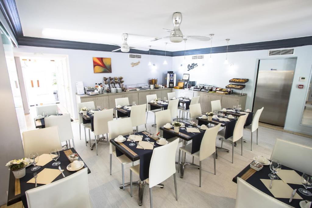 a dining room with tables and chairs and a kitchen at Cristal Hôtel & Spa in Cannes