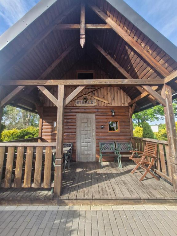 a wooden cabin with a porch with a bench at Domek letniskowy Łowisko Frączków 