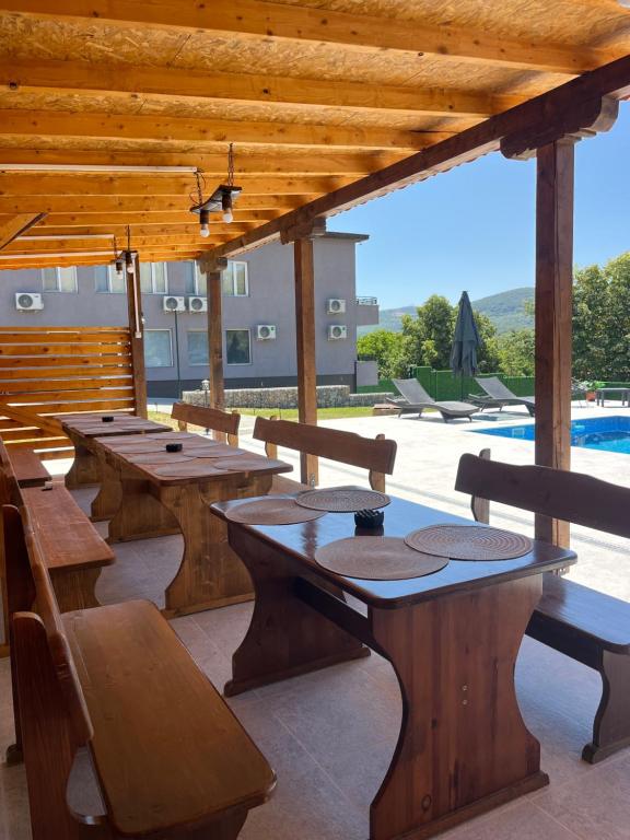 a patio with wooden tables and benches and a pool at Къща за гости Галанти Guest house Galanti in Orchenlar