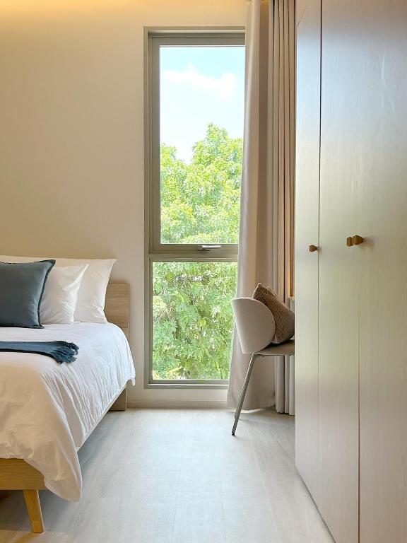 a bedroom with a bed and a window and a chair at Peace Nakhon Nayok in Nakhon Nayok