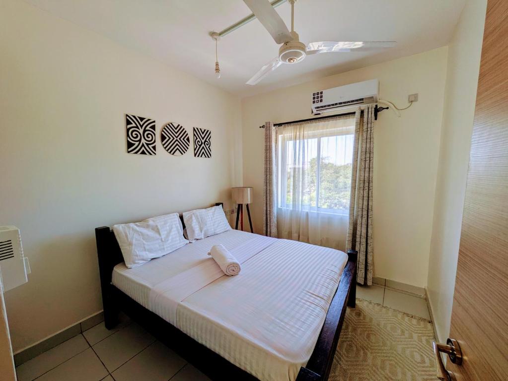 Un dormitorio con una cama con sábanas blancas y una ventana. en Buxton Point Lifestyle Stay with AC - Mombasa CBD, en Mombasa