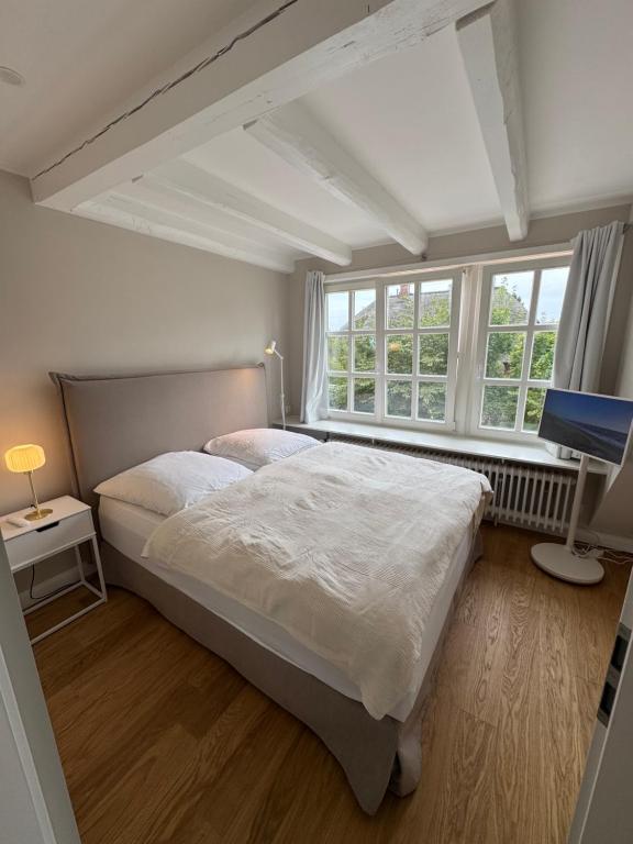 a bedroom with a large bed and a window at NEU Keitum - Moderne Gemütlichkeit unter Reet in Sylt