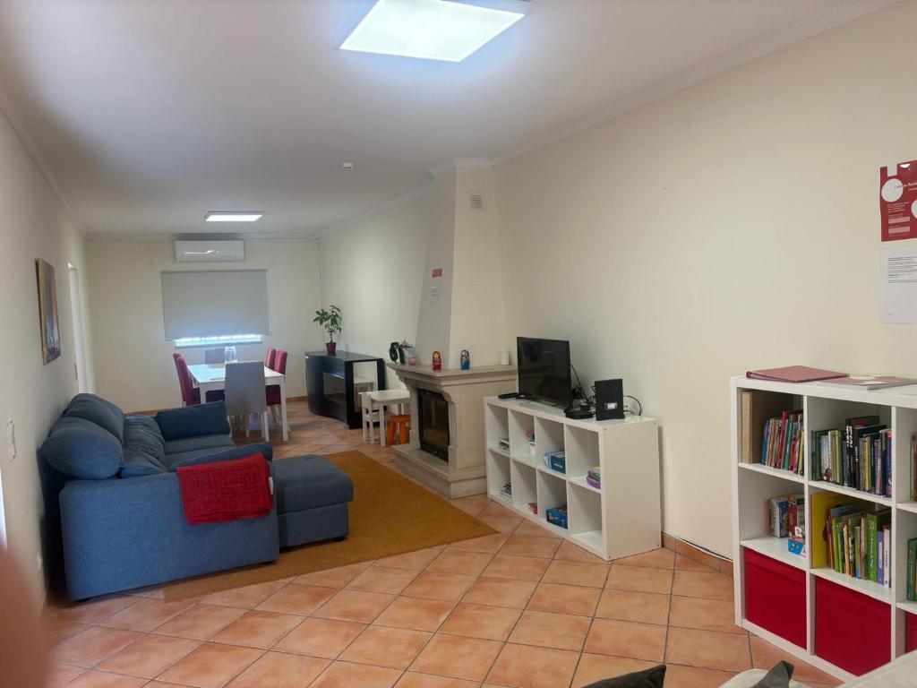 a living room with a couch and a tv and books at Casa de Férias Familiar in Olhão