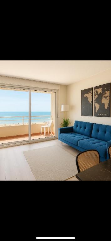 a living room with a blue couch and a view of the ocean at Vue sublime mer in Canet-en-Roussillon
