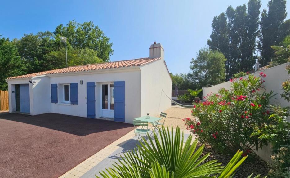 ein kleines weißes Haus mit einem grünen Tisch in einem Hof in der Unterkunft Charmante Maison à 500m de la plage in La Tranche-sur-Mer