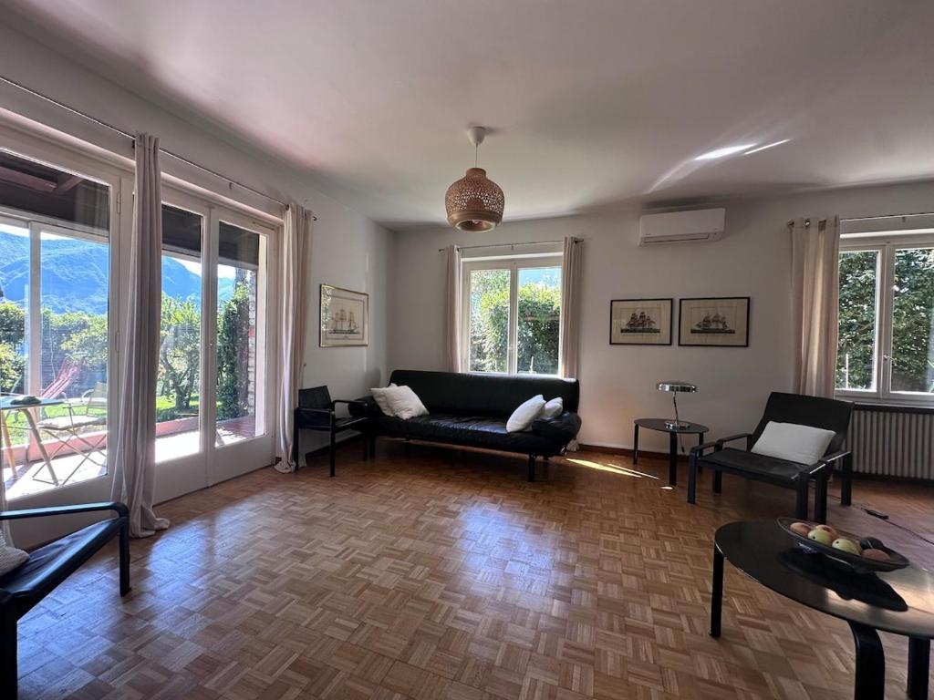 Una sala de estar con un sofá y sillas y ventanas. en Villa Lake View 2 Double Bedrooms, en Lugano