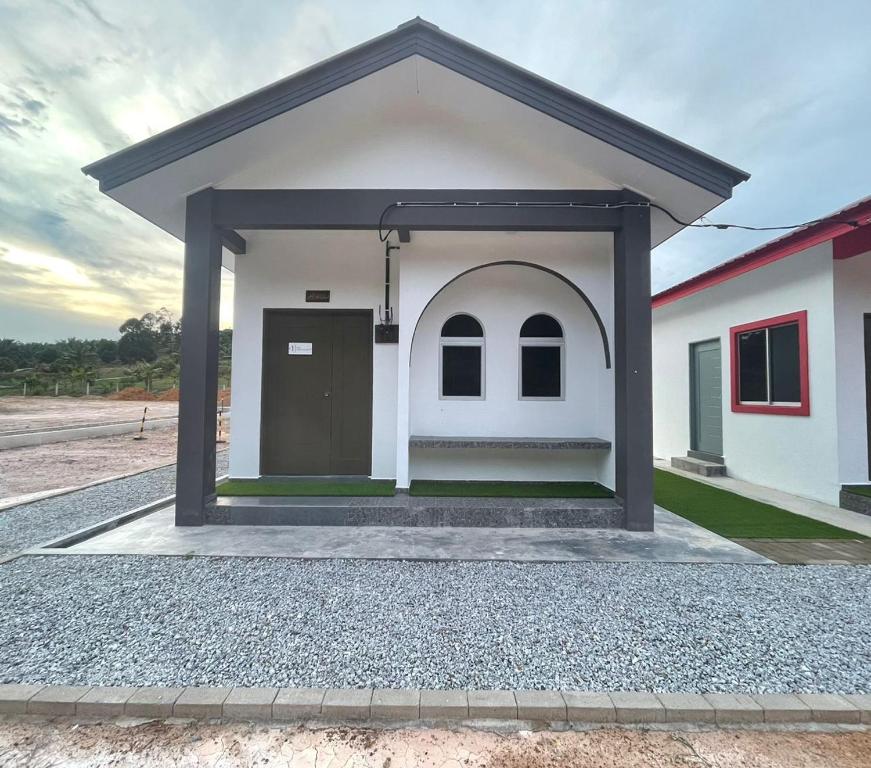 a small white house with a door in the middle at Casa de Alyzaa in Kampong Lendu