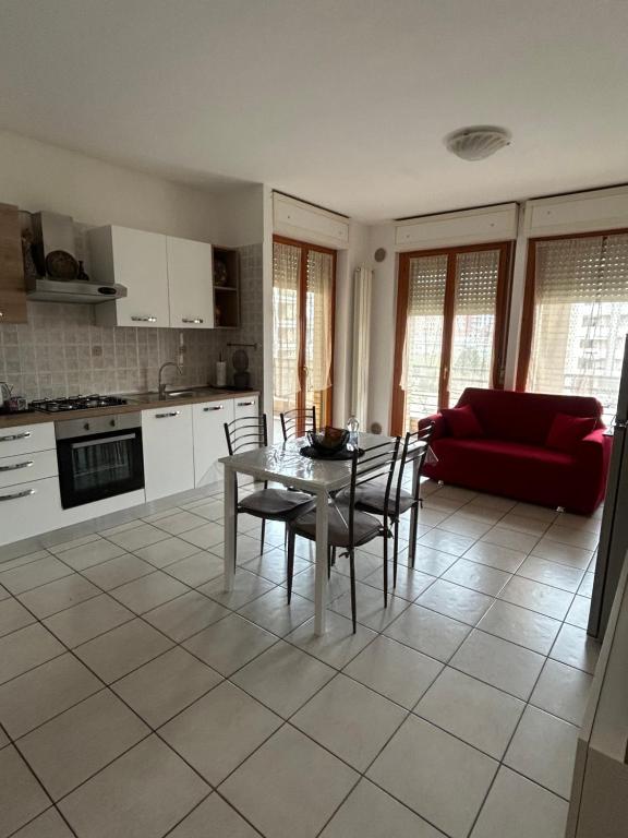a kitchen and living room with a table and a red couch at Casa Silvia - Accogliente bilocale a 5 minuti dalla stazione di Pescara Portanuova in Pescara
