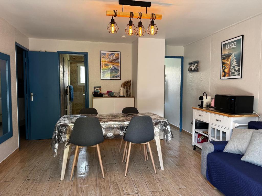 a living room with a table and chairs and a couch at Maisonnette au calme, T3, 6 pers résidence avec piscine et wifi privée proche lac et océan in Soustons