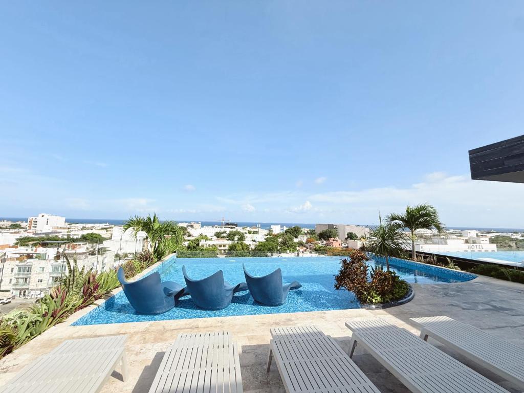 a swimming pool with chairs and a view of the ocean at NEW Luxury Modern Condo by Menesse in Playa del Carmen