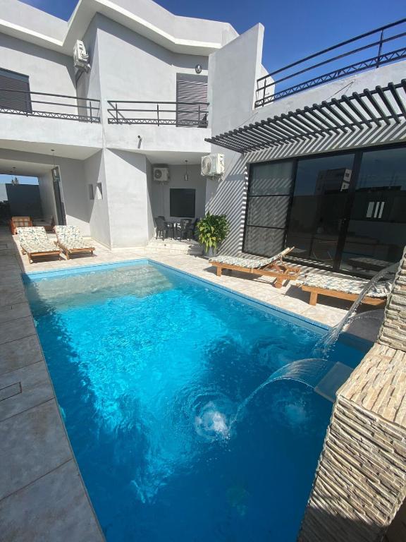 a swimming pool in front of a house at Villa Nafissa in Diass