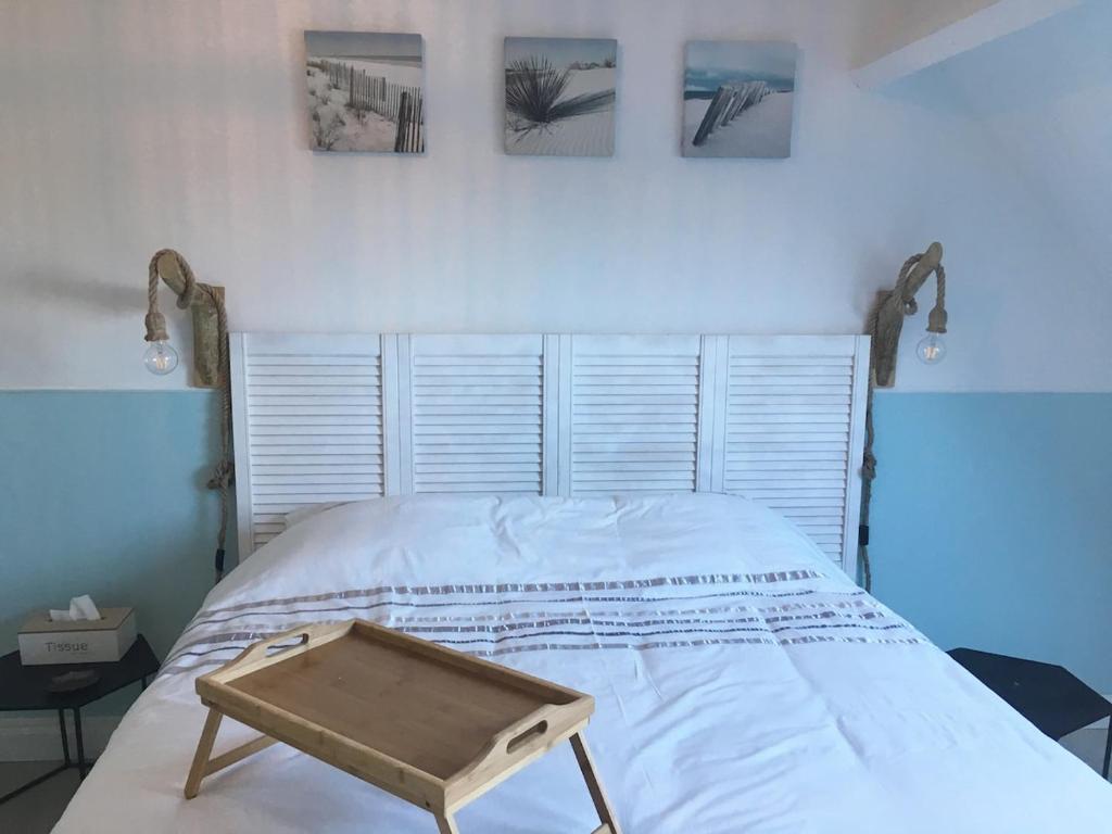 a bed with a wooden tray on top of it at Maison spacieuse avec jardin et feu de bois et parking gratuit pour 3 voiture in Le Crotoy