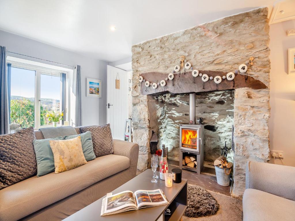 a living room with a couch and a stone fireplace at Hyfrydle Cottage in Pen-y-groes