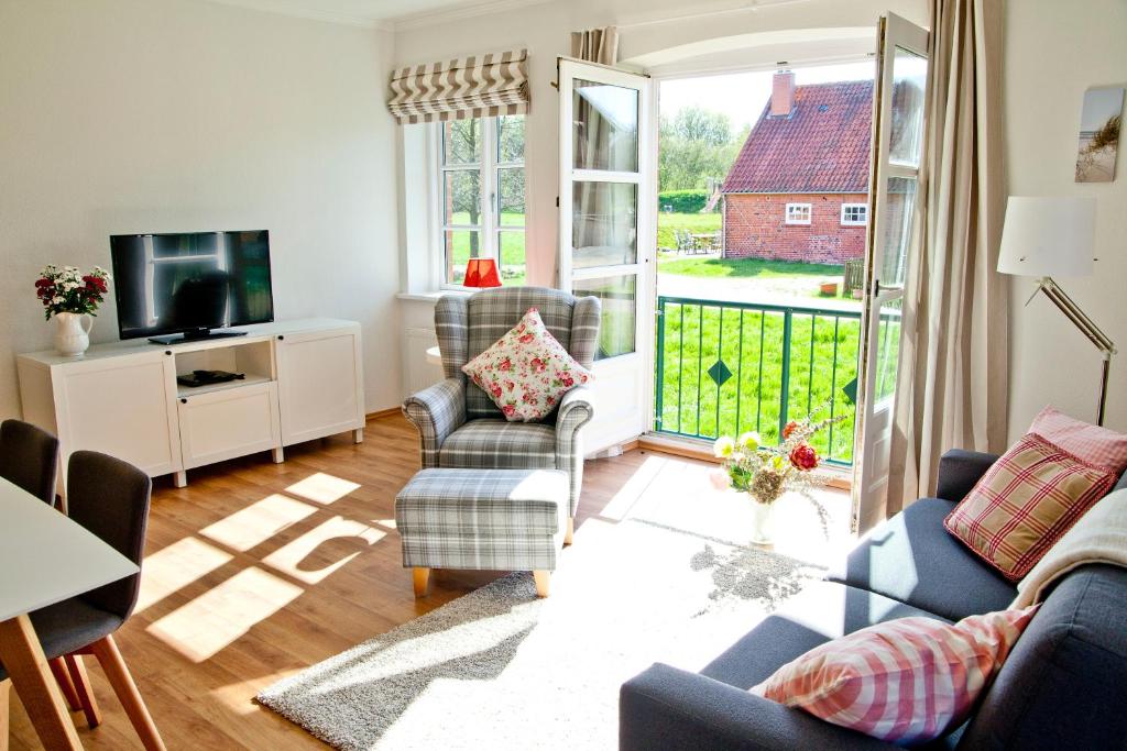 een woonkamer met een bank en stoelen en een televisie bij Ferienwohnung Ella in Scharbeutz