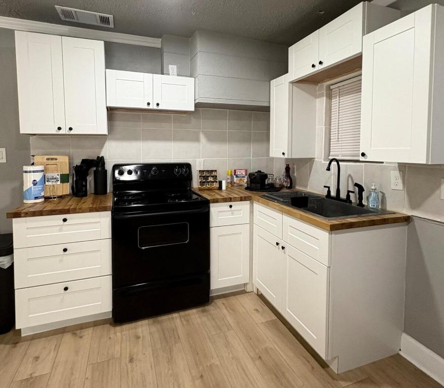 cocina con armarios blancos y lavavajillas negro en Cozy Stay 5 Min Ft Hood, en Killeen