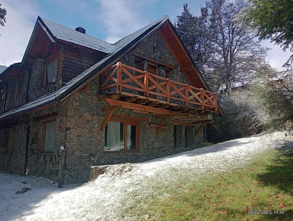 a house with a wooden balcony on the side of it at LA Nevadita, Chalet cabin located near the center- It includes suite room with double bed and another 2 bedrooms with two singles beds- Living room fireplace, Hot water, WI-FI in Villa La Angostura