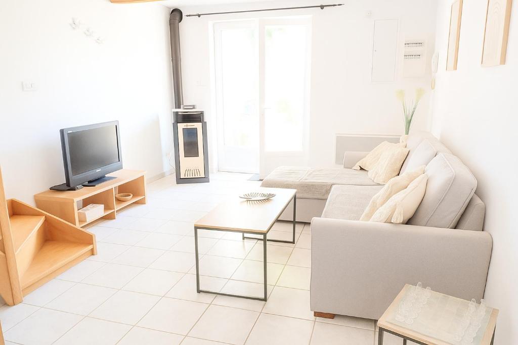 a white living room with a couch and a tv at Casa ARTEN in Alzonne