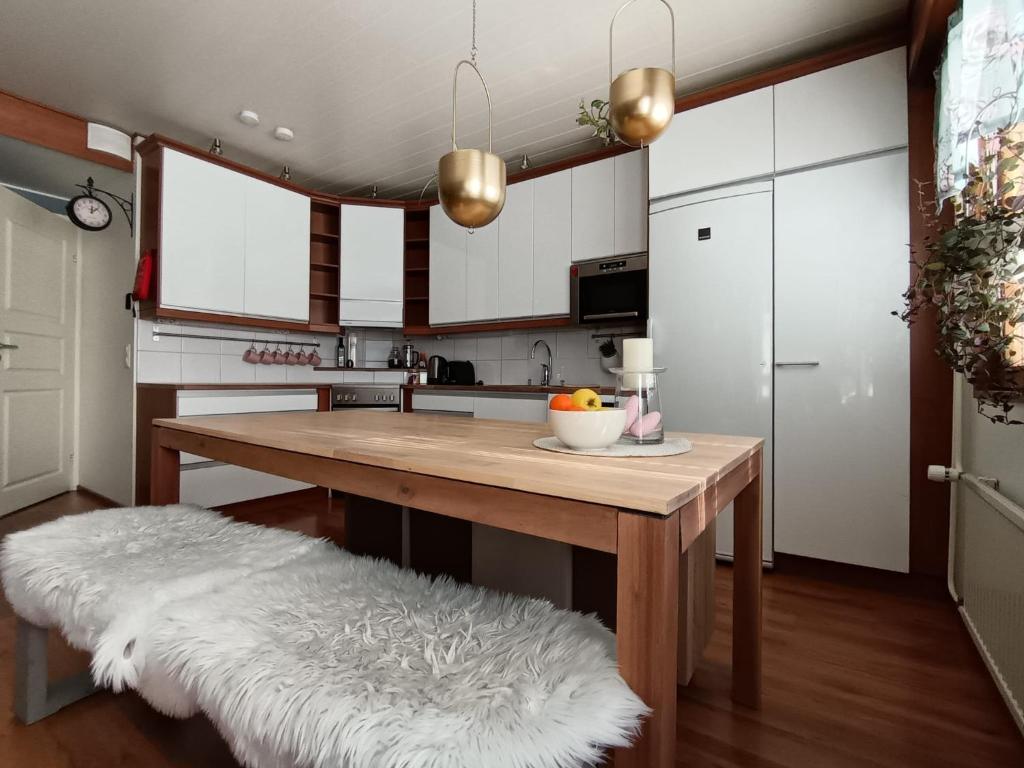 a kitchen with a wooden table and a white kitchen at Apartment Kallio, Rovaniemi Suomi in Hirvas